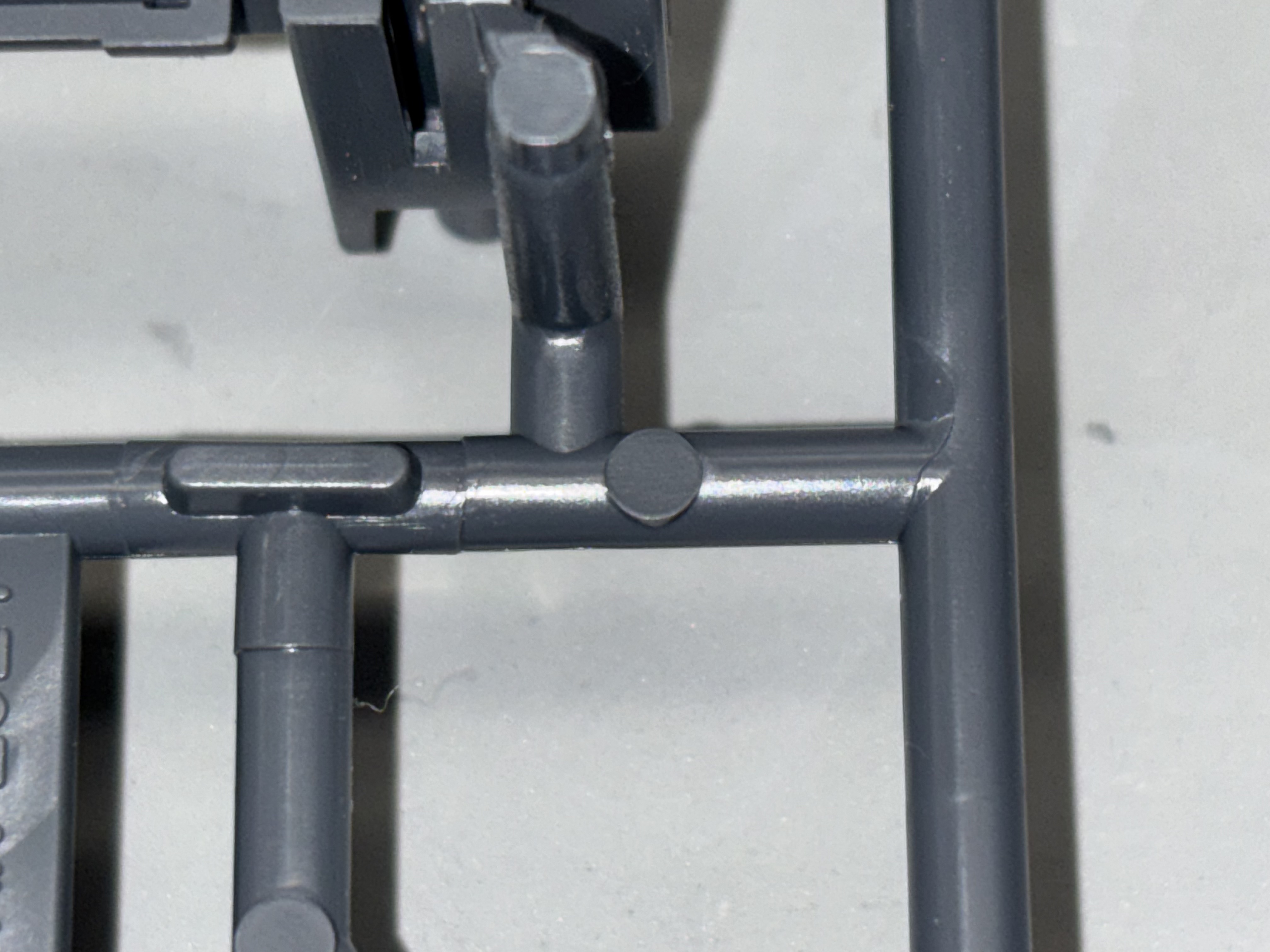 Close-up of a molded styrenic runner junction and gate geometry.